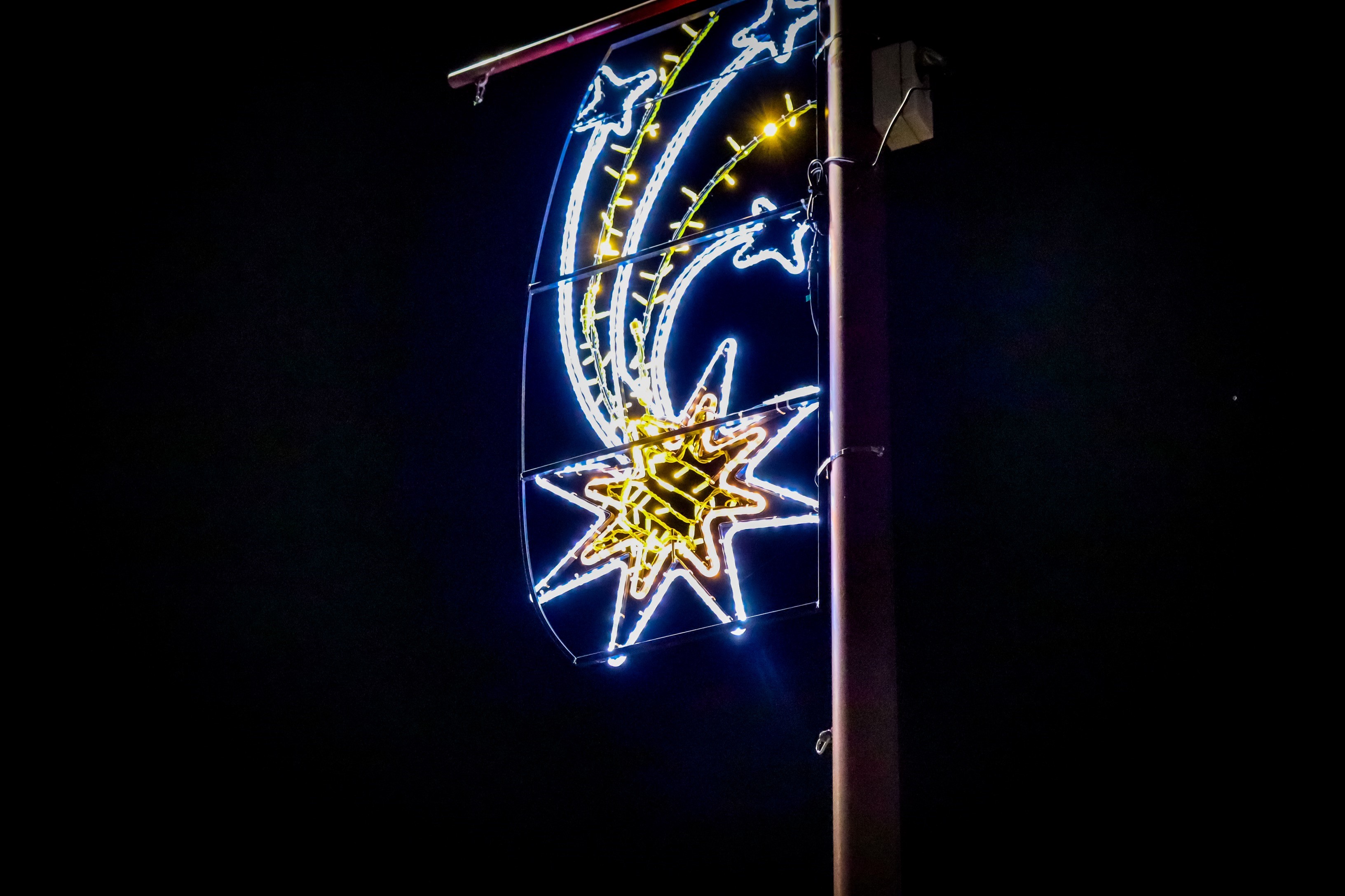 Black night sky with bright colourful neon light in the centre with trailing streamers of light behind.   