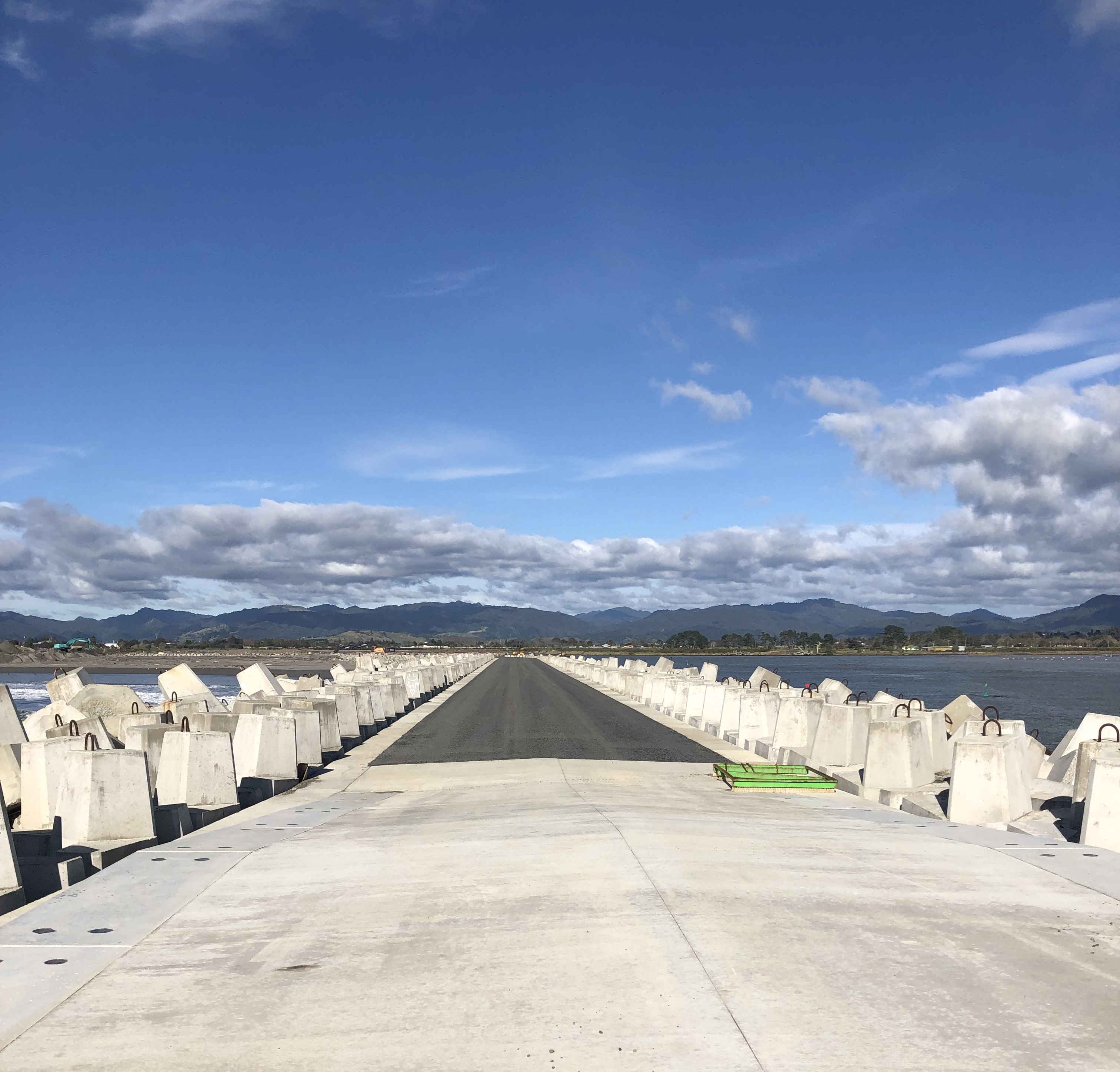 view looking out to sea along the length of the new seawalls - straight concrete centre with a jumble of hanbar units on either side. 